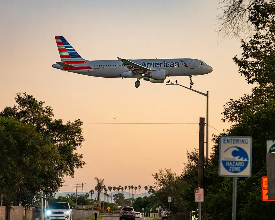 American Airlines Airbus A320 on final approach at dusk over a residential neighborhood