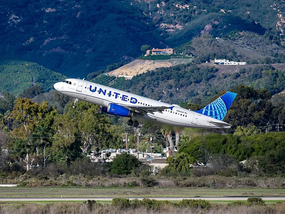 United Airlines Airbus A320 climbing out after takeoff with hills in the background