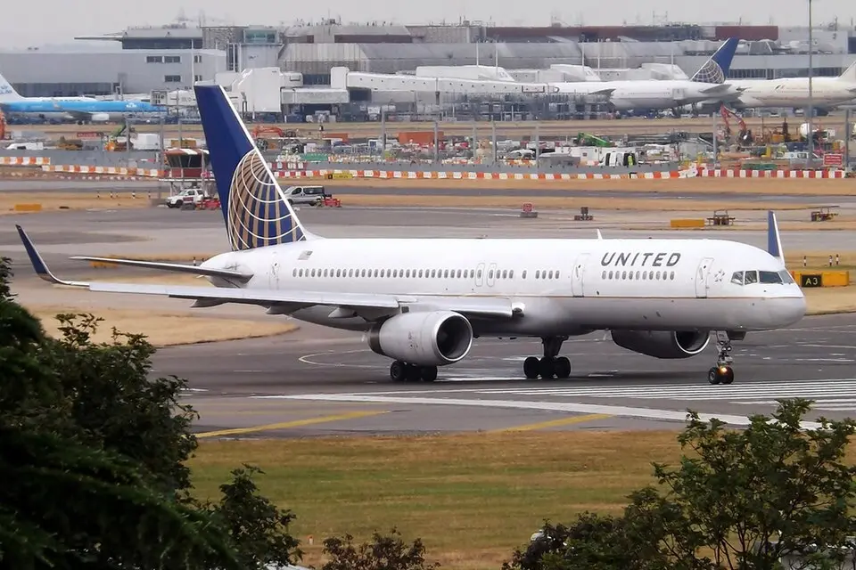 United Airlines Boeing 757 taxiing on the runway with other aircraft parked in the background